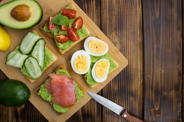 Sandviç kahverengi ahşap zemin üzerinde avokado ve farklı malzemelerle. Üstten görünüm. Kopya alanı.