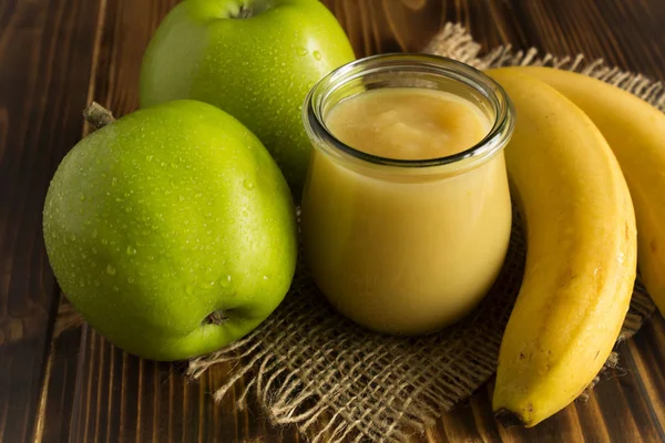 Puree with apples and banana on the rustic background