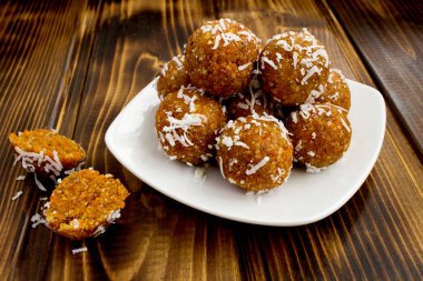 Enerji topları kuru kayısı ve kahverengi ahşap zemin üzerinde beyaz tabak içinde Hindistan cevizi cips ile