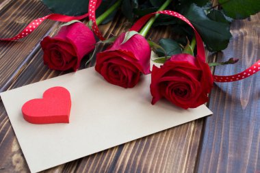 Zarf, kırmızı gül ve kalp ahşap arka plan üzerinde