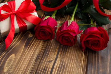 Kırmızı gül ve hediye kutusu ahşap arka plan üzerinde