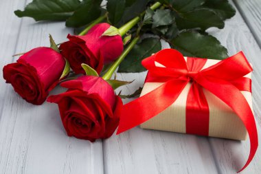 Kırmızı gül ve hediye kutusu gri ahşap arka plan üzerinde