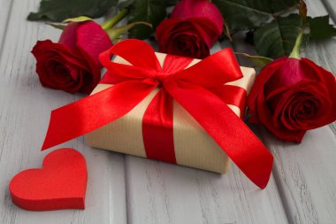 Hediye kutusu, kırmızı gül ve kalp gri ahşap arka plan üzerinde