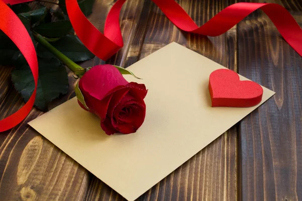 Zarf, kırmızı gül ve kalp ahşap arka plan üzerinde