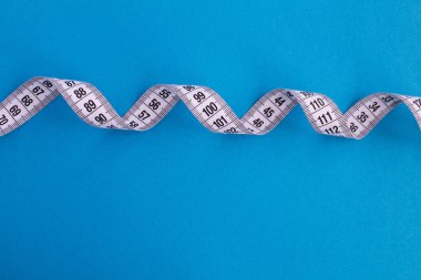 Mavi zemin üzerine beyaz santimetre. Üstten görünüm. Diyet en az kavramı. Kopya alanı.