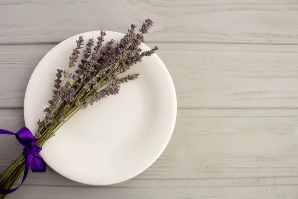 Table setting with the white plate and dried lavender on the grey wooden background .Top view.Copy space.