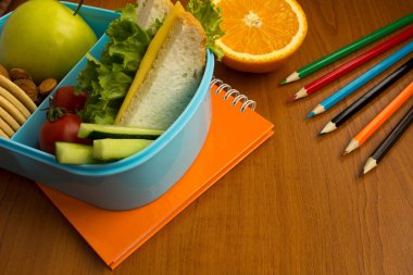 Okul öğle yemeği kutusu, kalem ve defter masada