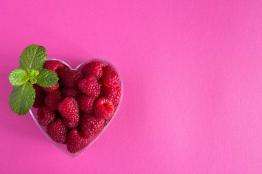 Ahududu pembe arka plan üzerinde kalp şeklinde. Üstten görünüm. Kopya alanı.