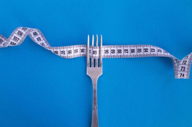 Beyaz santimetre ve mavi arka plan üzerinde çatalı. Üstten görünüm. Kopya alanı.