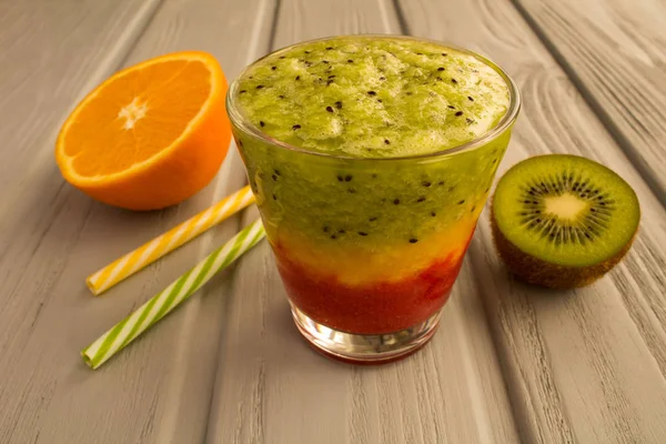 Colorful smoothies with kiwi,orange and strawberry on the grey wooden background