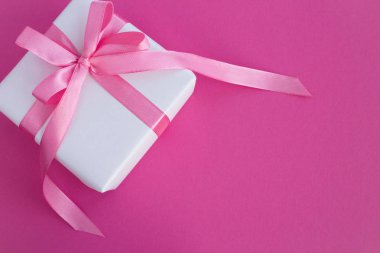 Koyu pembe arka plan üzerinde pembe Fiyonklu hediye paketi. Üstten görünüm. Uzay kopyalayın. Portre.