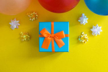 Turuncu yay ve sarı arka plan üzerinde renkli balonlar ile Hediyelik kullanır. Üstten görünüm. Kopya alanı.