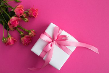 Pembe fiyonk ve koyu pembe arka plan üzerinde pembe gül ile Hediyelik kullanır. Üstten görünüm. Kopya alanı.