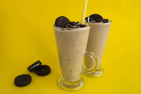Milkshake with chocolate biscuit  and cocoa in the glass on the yellow background.Closeup.Copy space.