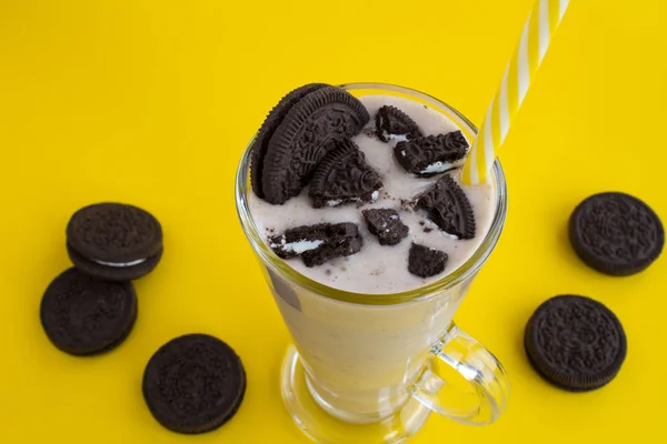 Milkshake with chocolate biscuit  and cocoa in the glass on the yellow background.Top view.