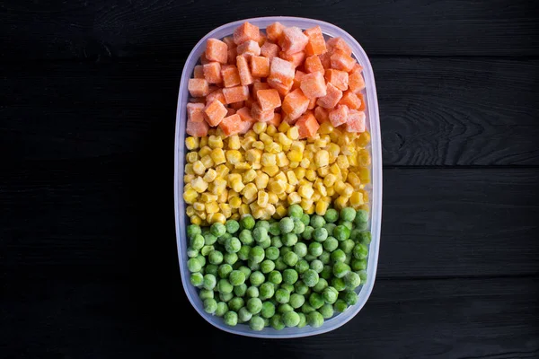 Frozen vegetables in the box on the black wooden background.Top view.Copy space.Healthy food ingredients.