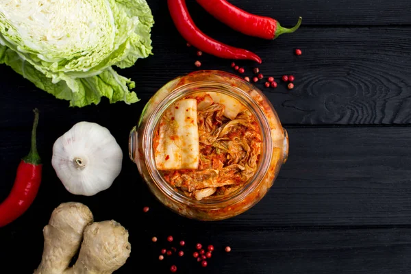 Kimchi cam kavanoz ve malzemelerin üzerine siyah ahşap arka plan. Üstten görünüm. Kopya alanı.