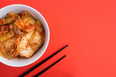 Kimchi beyaz plaka ve kırmızı zemin üzerine siyah çubuklar. Üstten görünüm. Kopya alanı.