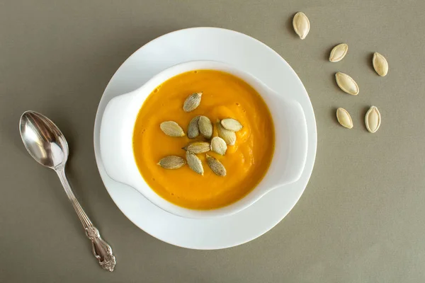 Soup with pumpkin  in the white plate on the grey background.Top view.