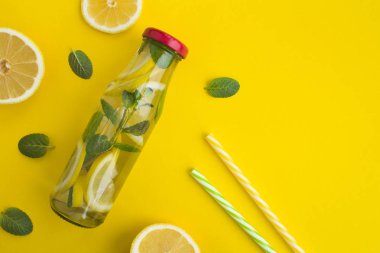 Limon ve nane sarı zemin üzerine cam şişede su detoks. Üstten görünüm. Kopya alanı.