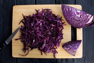 Siyah ahşap zemin üzerine kahverengi kesme tahtası üzerinde kıyılmış taze mavi lahana. Üstten Görünüm.