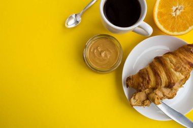 Kahvaltı: kruvasan fıstık Yapıştır siyah ve turuncu sarı zemin üzerine. Üstten Görünüm. Kopya alanı.