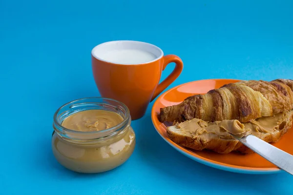 Kahvaltı Kruvasan Fıstık Yapıştırın Mavi Arka Plan Üzerinde Süt Ile — Stok fotoğraf