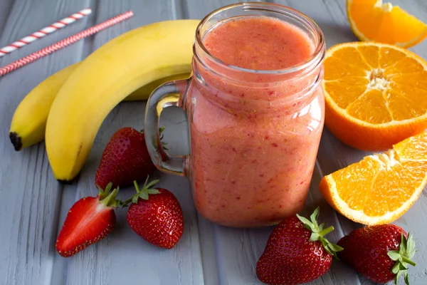 Smoothie  from strawberry, banana  and  orange on the grey  wooden background