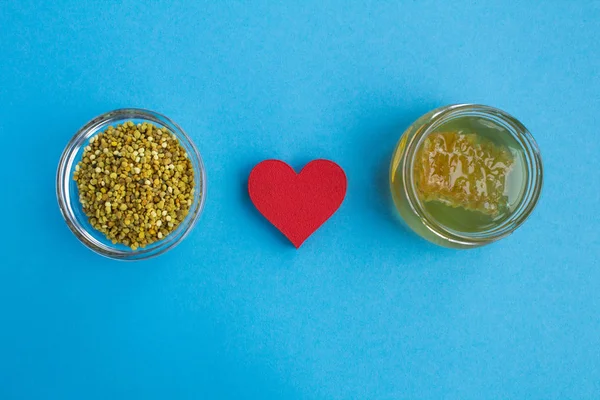 Bee pollen,red  heart and honey on the blue background.Health  products.Top view.Copy space.