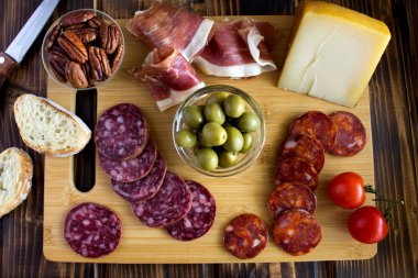 İspanyol jamon, sosis ve kesme tahtası kahverengi ahşap zemin üzerinde beyaz peynir. Üstten Görünüm.