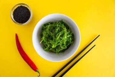 Deniz yosunu ve Sarı zemin üzerine beyaz tabak Susam salata. Üstten Görünüm.