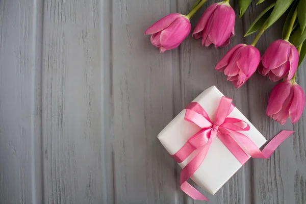 Pembe fiyonk ve gri ahşap arka plan üzerinde Pembe Lale ile Hediyelik kullanır. Üstten Görünüm. Kopya alanı.