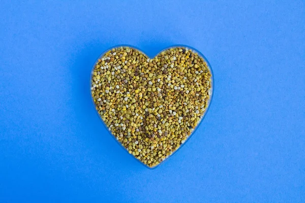 Bee pollen  in the heart shape  on the blue background.Top view.Copy space.