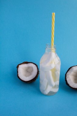 Su cam şişe mavi zemin üzerine Hindistan cevizi ile detoks. Kopya alanı.