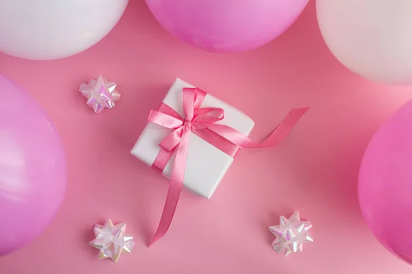 Gift with  pink and white balloons  on the pink background.Top view.