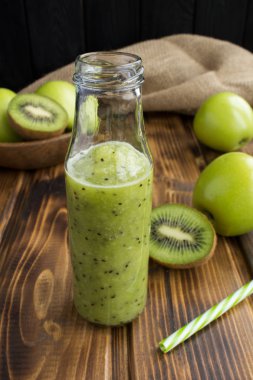 Rustik ahşap arka plan üzerinde cam şişede kivi ve yeşil elma ile smoothies
