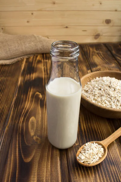 Oat milk in the glass bottle on the rustic wooden background.Healthy drink.