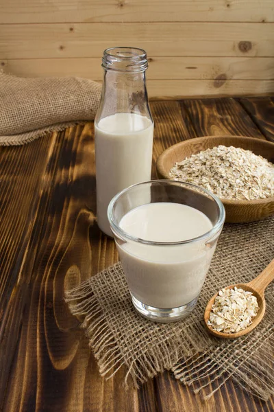 Oat milk in the glass on the rustic wooden background.Healthy drink.