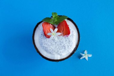 Mavi arka planda Hindistan cevizi Chia ve çilek ile Pudding. Üst görünüm.