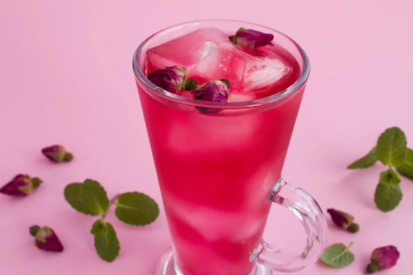 Cold lemonade or tea with pink roses on the pink background.Closeup.