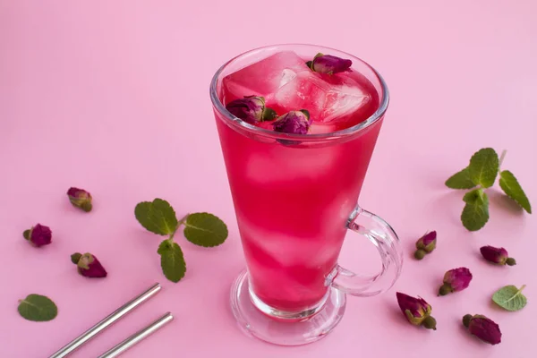 Cold lemonade or tea with pink roses on the pink background