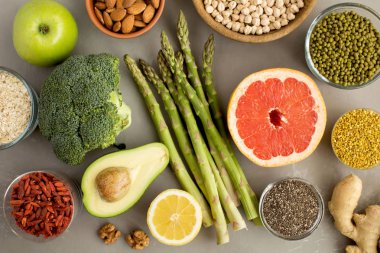 Superfood veya vejetaryen gıda konsepti. Gri beton arka planda sebze, meyve, bakliyat, fındık ve arı polen. Üst görünüm.