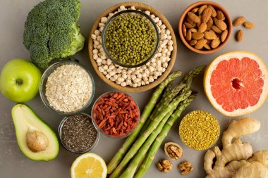 Superfood veya vejetaryen gıda konsepti. Gri beton arka planda sebze, meyve, bakliyat, fındık ve arı polen. Üst görünüm.