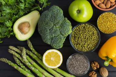 Superfood veya vejetaryen gıda konsepti. Siyah ahşap arka planda sebze, meyve, bakliyat, fındık ve arı polen. Üst görünüm.