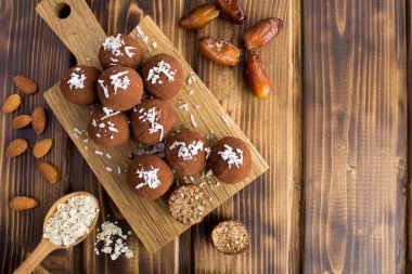 Hindistan cevizi cipsi ile Enerji topları, badem, yulaf tahıl ve kahverengi ahşap arka plan üzerinde kesme tahtası nda tarihler. Üst te. Kopyalama alanı.