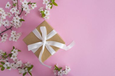 Pembe arka plan üzerinde beyaz yay ve çiçekli ağaç dalları ile Hediye. Üst te. Kopyalama alanı.