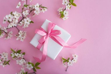 Pembe arka plan üzerinde pembe yay ve çiçekli ağaç dalları ile Hediye. Üst te. Kopyalama alanı.