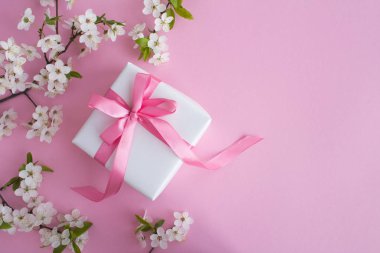 Pembe arka plan üzerinde pembe yay ve çiçekli ağaç dalları ile Hediye. Üst te. Kopyalama alanı.