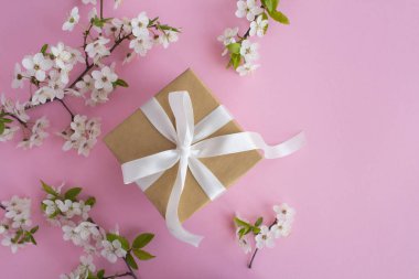 Pembe arka plan üzerinde beyaz yay ve çiçekli ağaç dalları ile Hediye. Üst te. Kopyalama alanı.