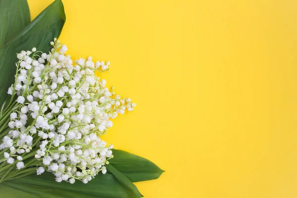 Spring or summer background.Bouquet of lily of the valley on the yellow background.Top view.Copy space.Spring flowers concept.